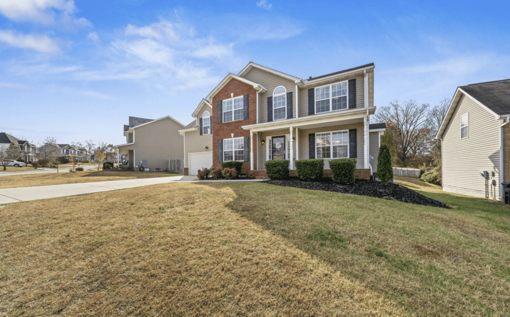 Spacious two-story brick and siding suburban house with a manicured lawn.