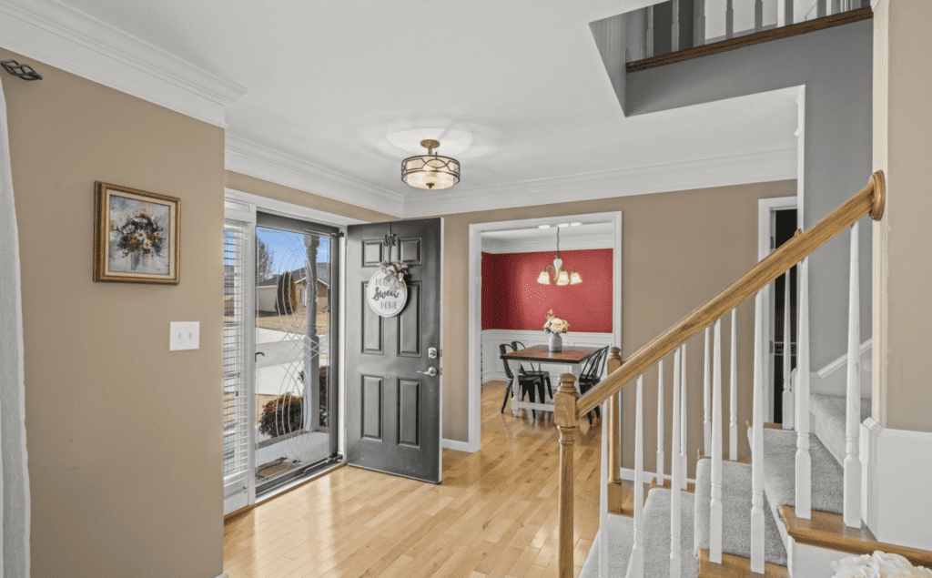 Open front door revealing a bright entryway and dining room.