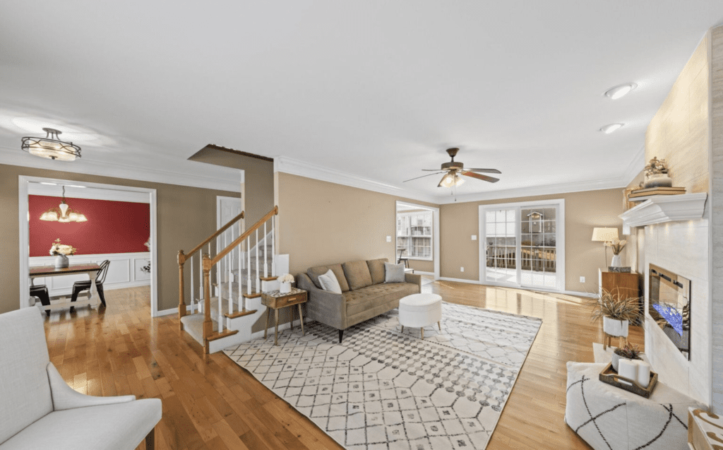 Bright living room with hardwood floors, neutral furnishings, and large windows.