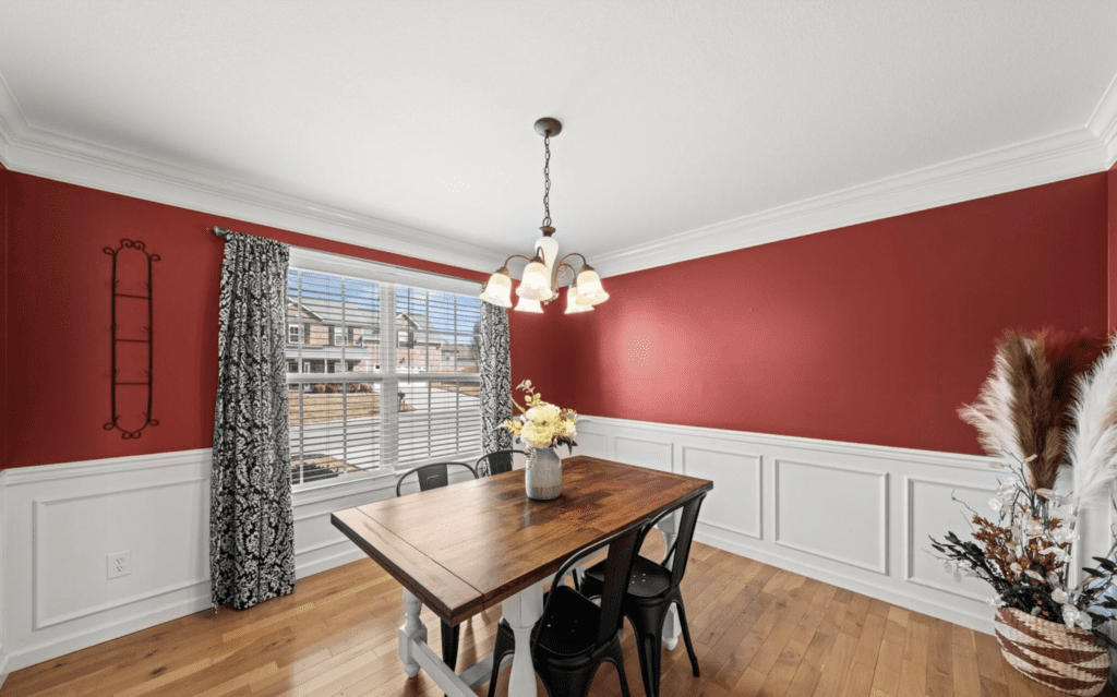 Bright dining room with wooden table and red accent wall.