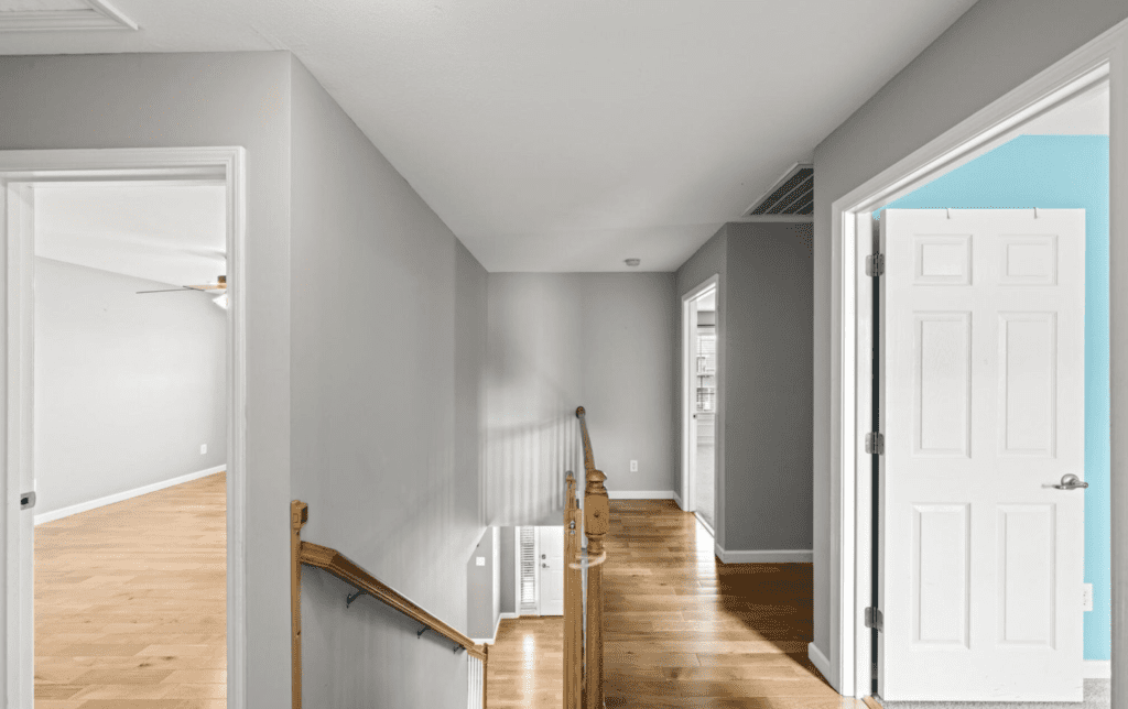 Bright hallway with wooden floors and gray walls.