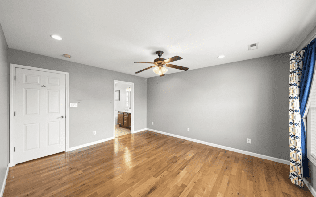 Empty room with wooden floor and ceiling fan.