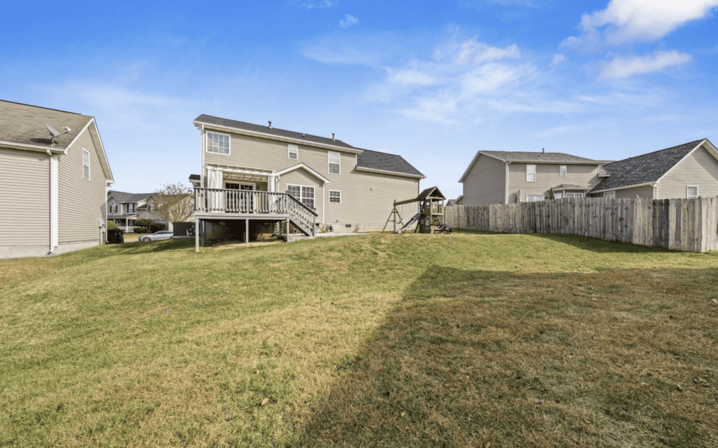 Backyard with a wooden deck and playset under a clear blue sky.