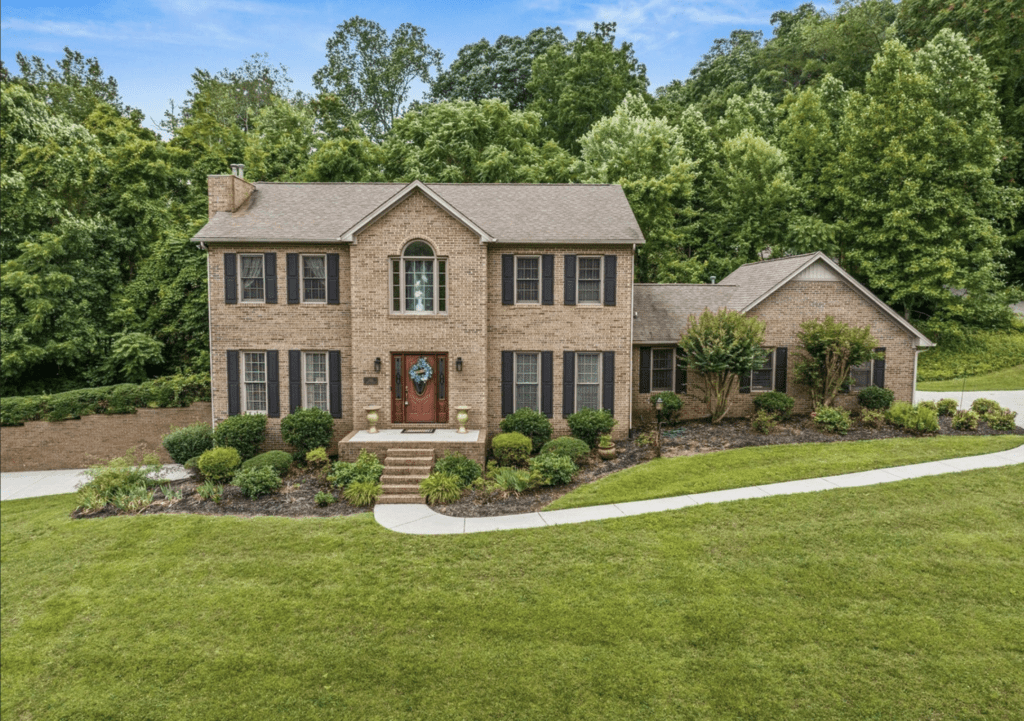 A large two-story brick house with a manicured lawn.