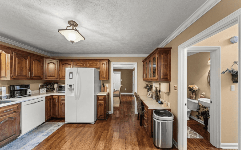 Spacious kitchen with wooden cabinets, white appliances, and hardwood floors.