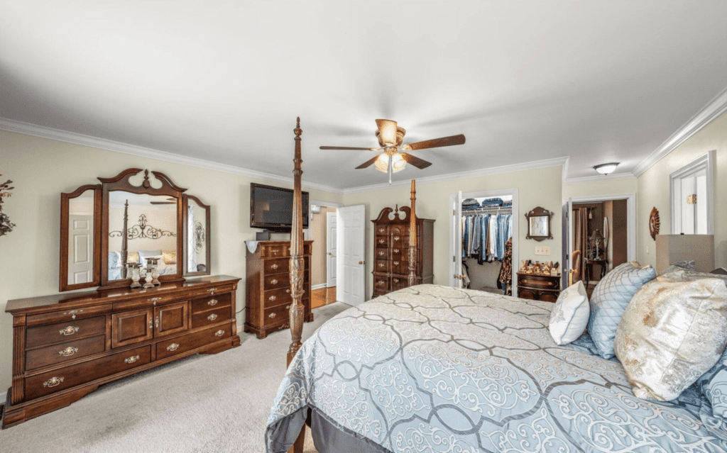 Spacious bedroom with classic wooden furniture and a ceiling fan.