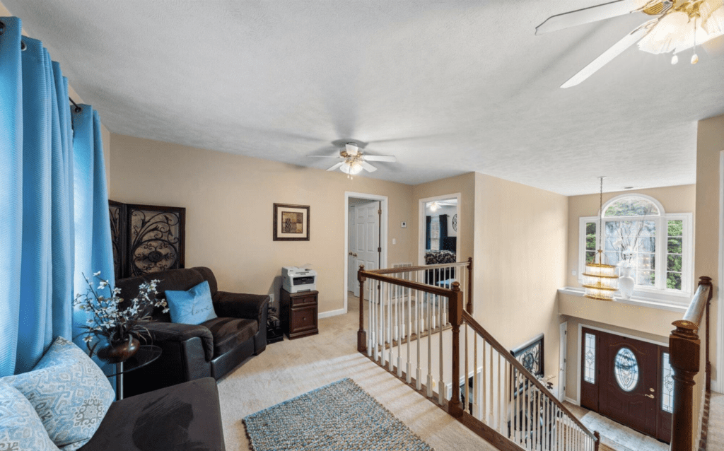 Cozy living area with ceiling fan and staircase railing.