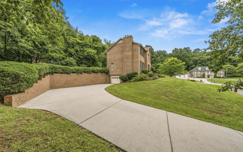 A large brick house with a spacious driveway and green lawn.