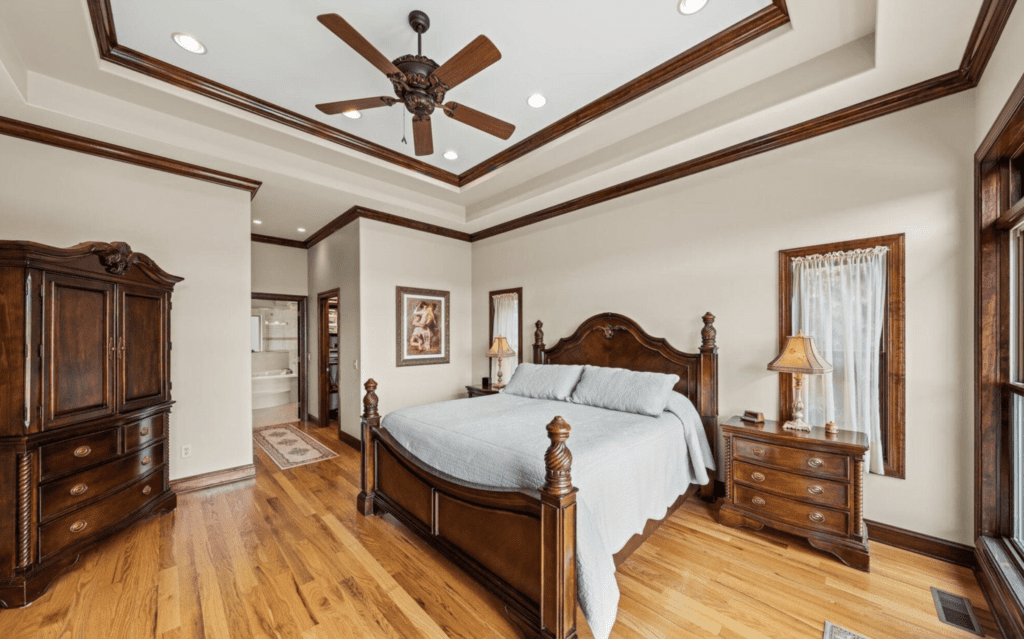 Elegant bedroom with wooden furniture and ceiling fan.