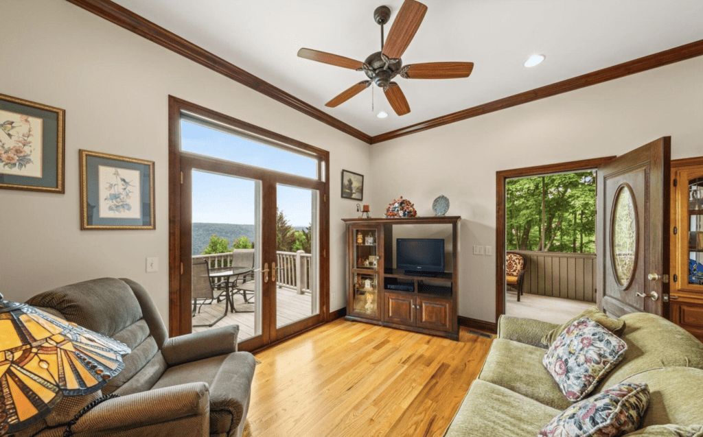 Cozy living room with wooden floors, ceiling fan, and large glass doors leading to a balcony.