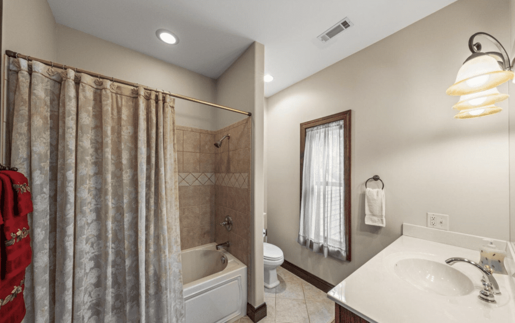 Cozy bathroom with shower, toilet, and window with curtain.