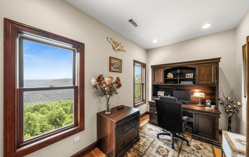 Bright home office with scenic window views and wooden furniture.