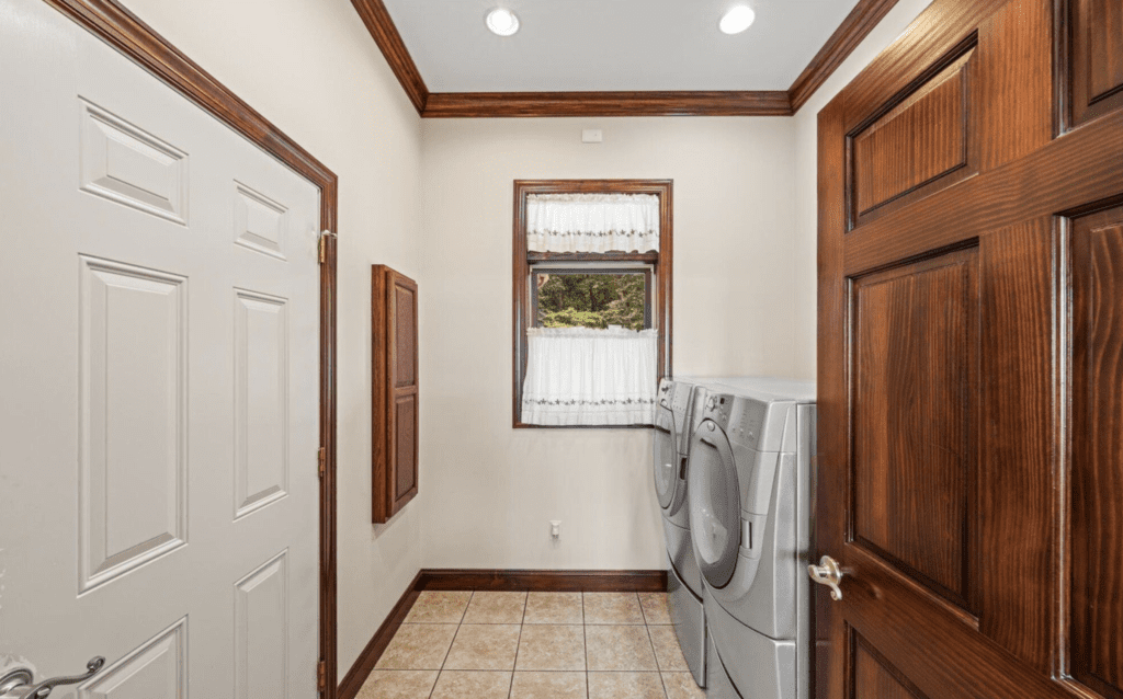 Laundry room with washer, dryer, and a window with curtains.