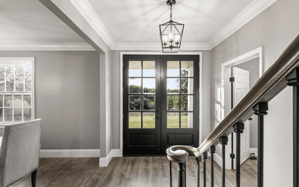 Elegant entryway with black double doors and gray walls.