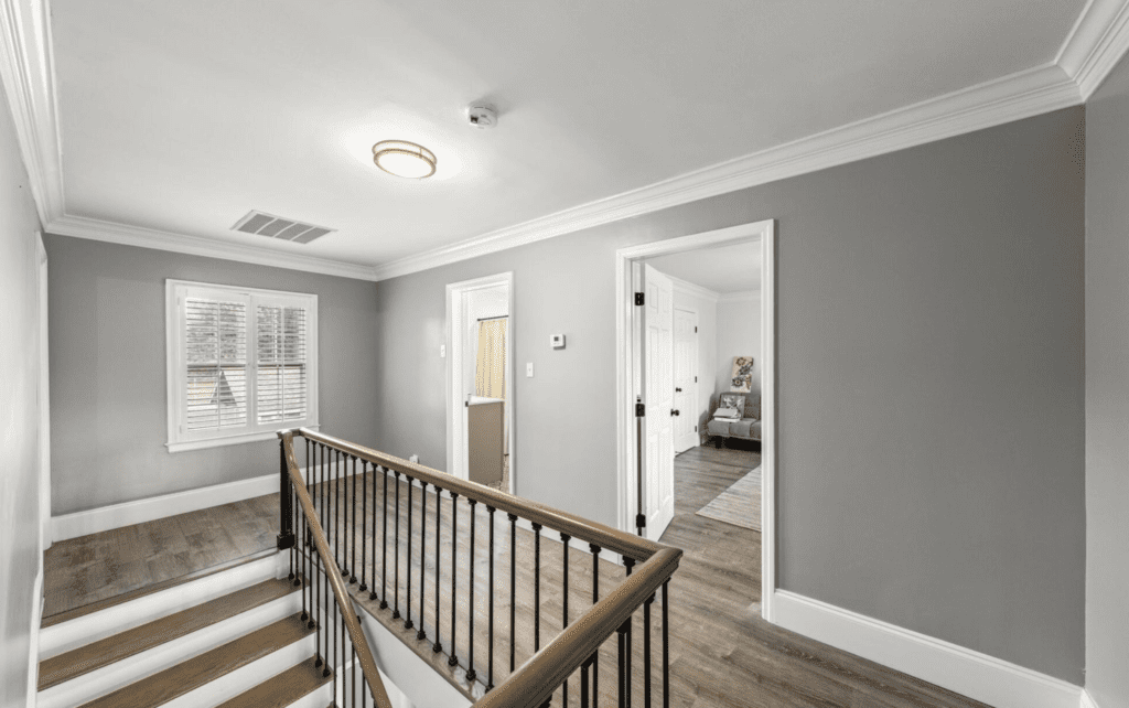 Bright hallway with wooden railing and carpeted stairs.