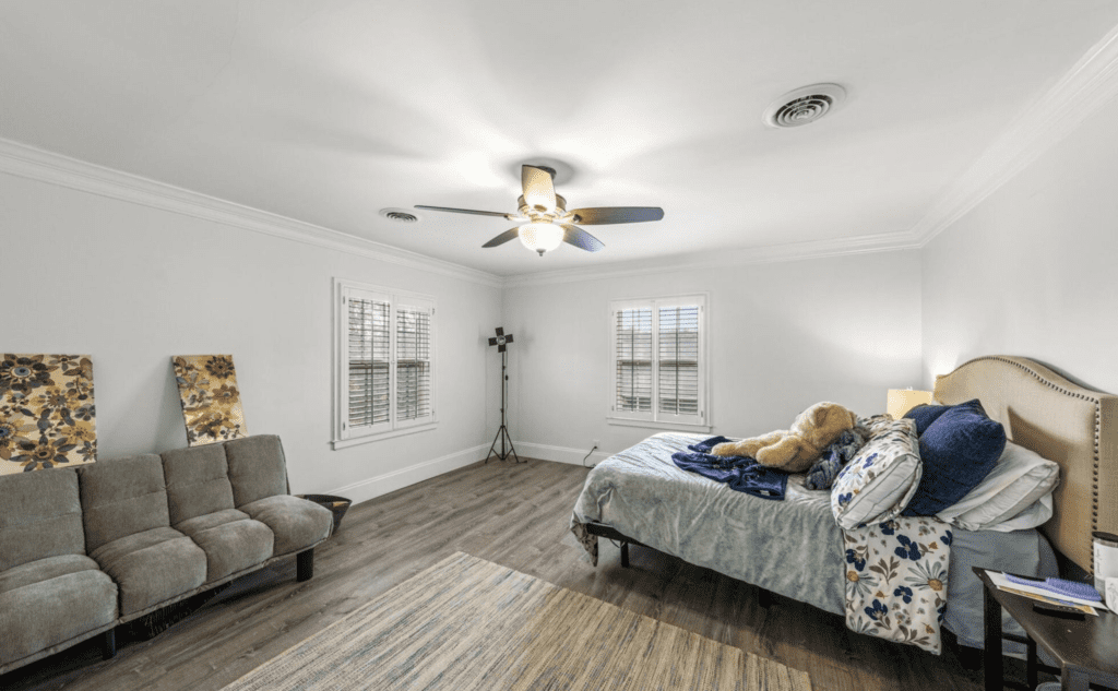 Bright bedroom with a ceiling fan and cozy bedding.
