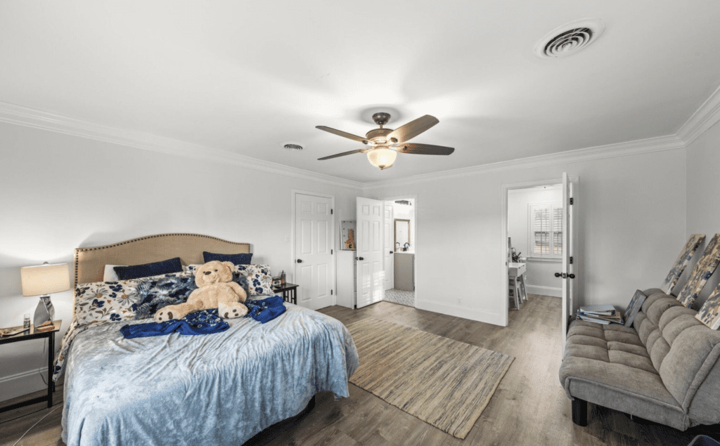Spacious bedroom with light wood flooring and a ceiling fan.