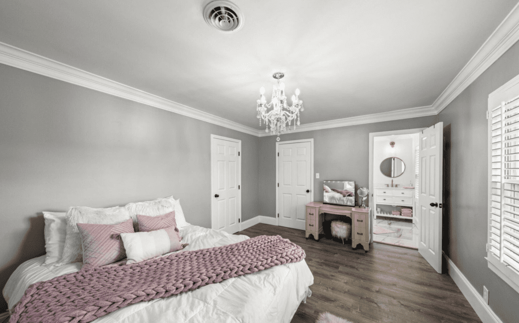 Elegant bedroom with soft gray walls, a chandelier, and cozy bedding.