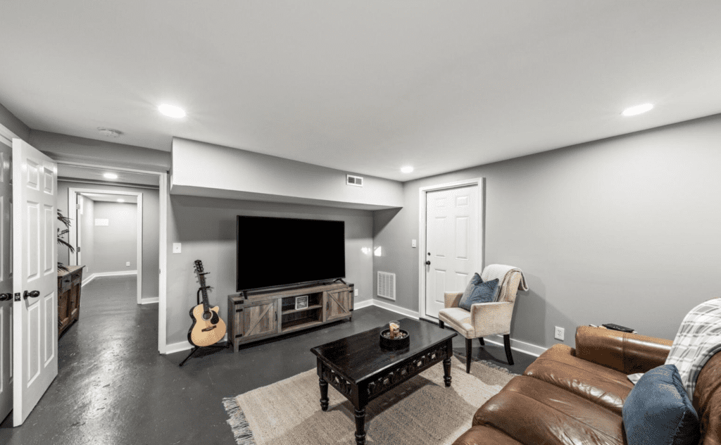 Cozy modern living room with a large TV and guitar.
