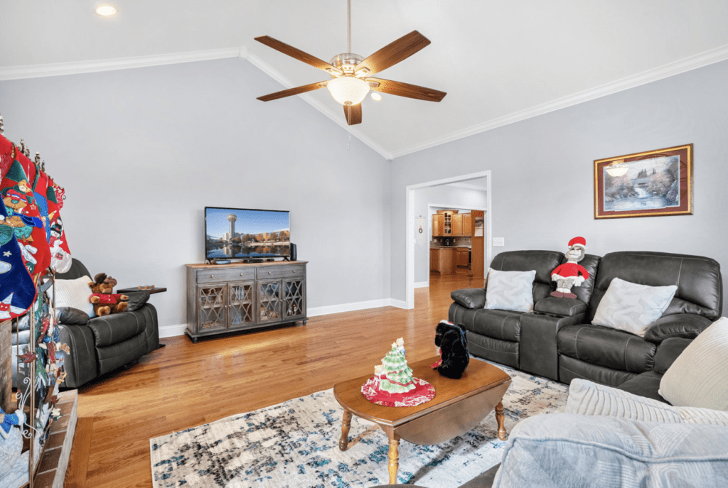Cozy living room with a ceiling fan, gray walls, and comfortable leather seating.