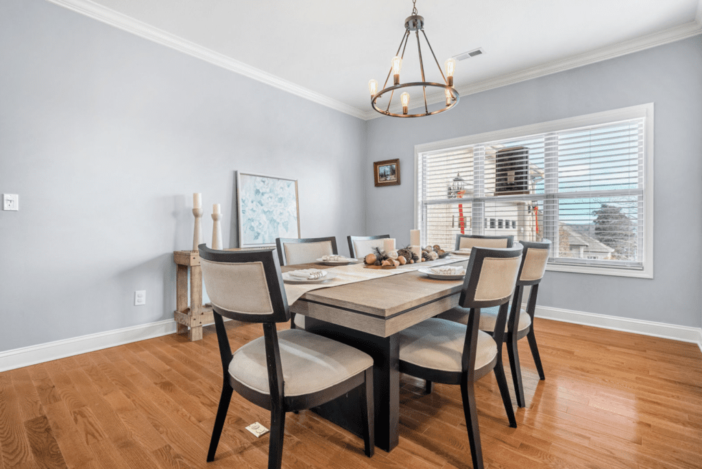 Bright dining room with wooden table and beige cushioned chairs.