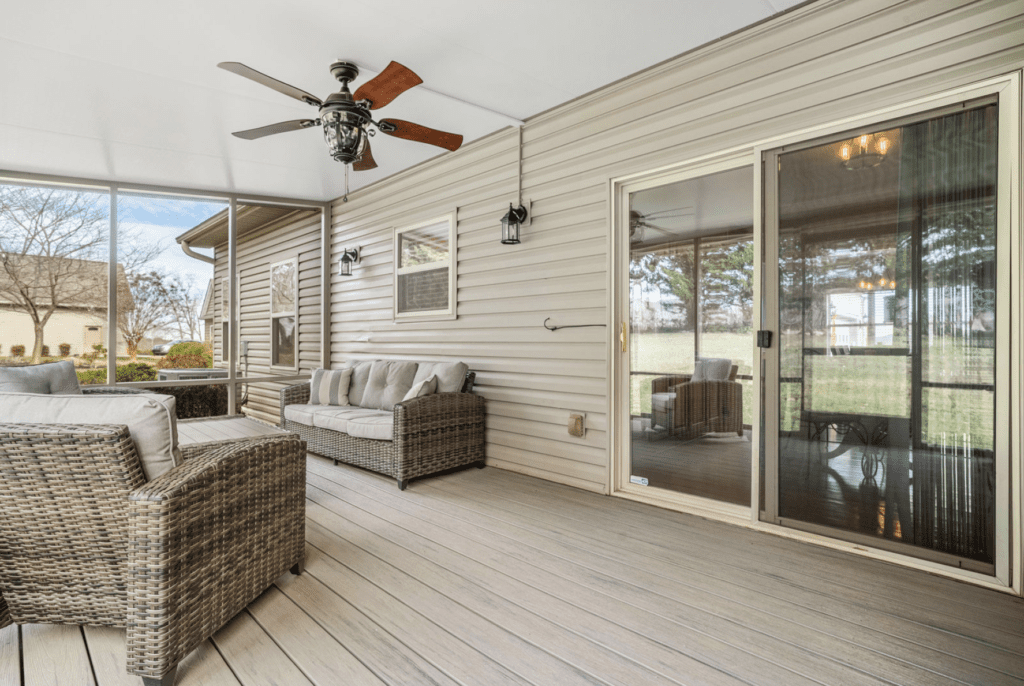 Cozy outdoor patio with wicker furniture and ceiling fan under a covered deck.
