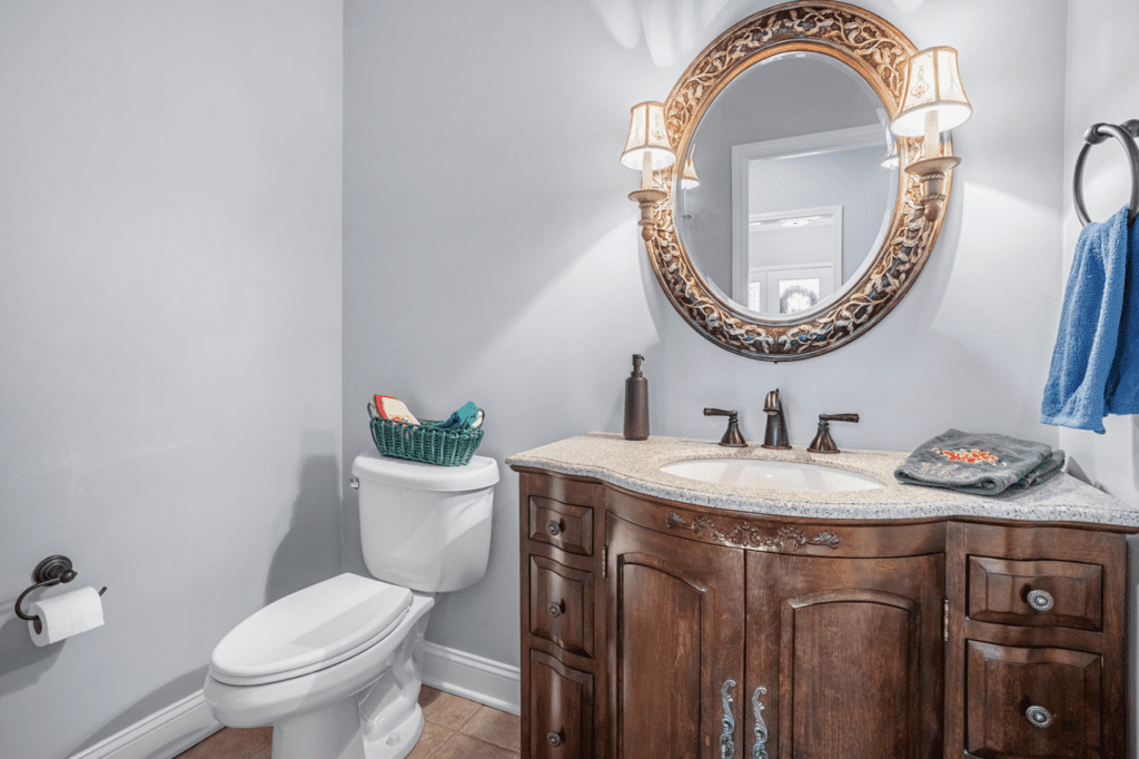 Elegant bathroom with wooden vanity and ornate mirror.