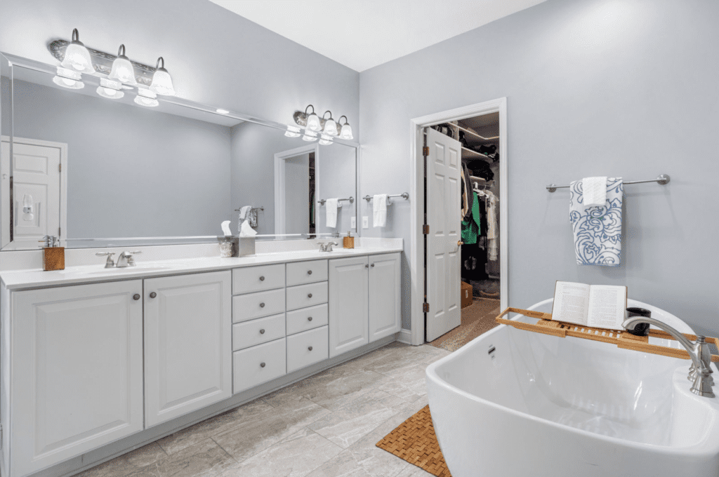 Modern bathroom with double sinks, large mirror, and a freestanding bathtub.