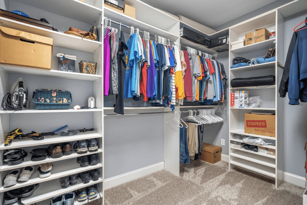 A well-organized walk-in closet with clothes, shoes, and storage boxes.