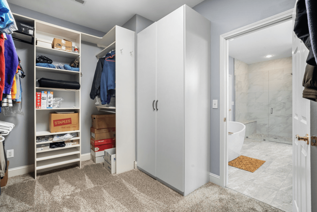 A modern walk-in closet with organized shelves and a white wardrobe.
