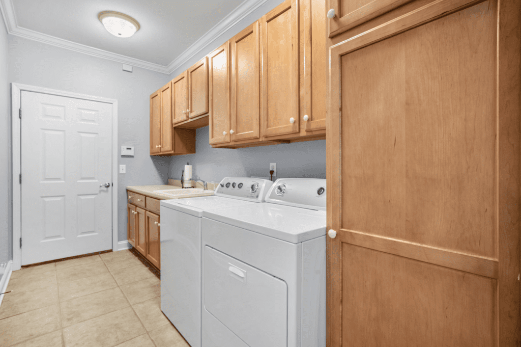 Laundry room with washer, dryer, and wooden cabinets.