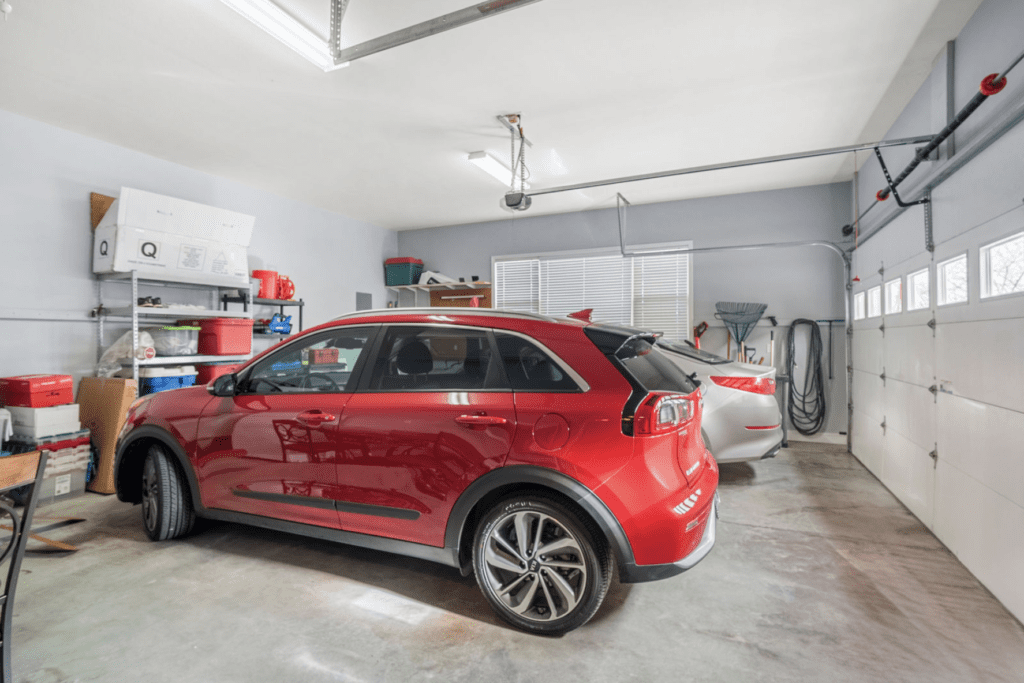 Two cars parked inside a clean, organized garage with shelves and tools.
