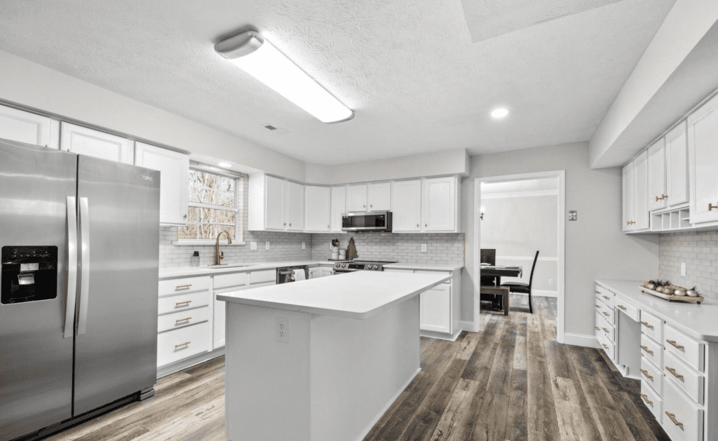 Modern white kitchen with island and wooden floors.
