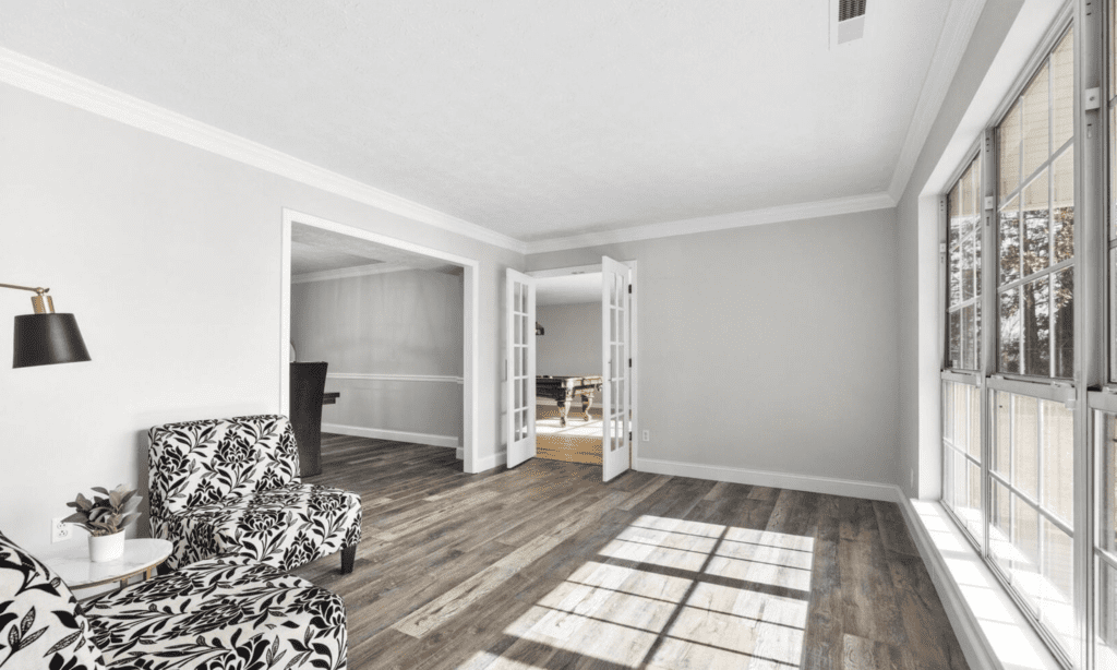 Bright empty room with wooden floors and open double doors.