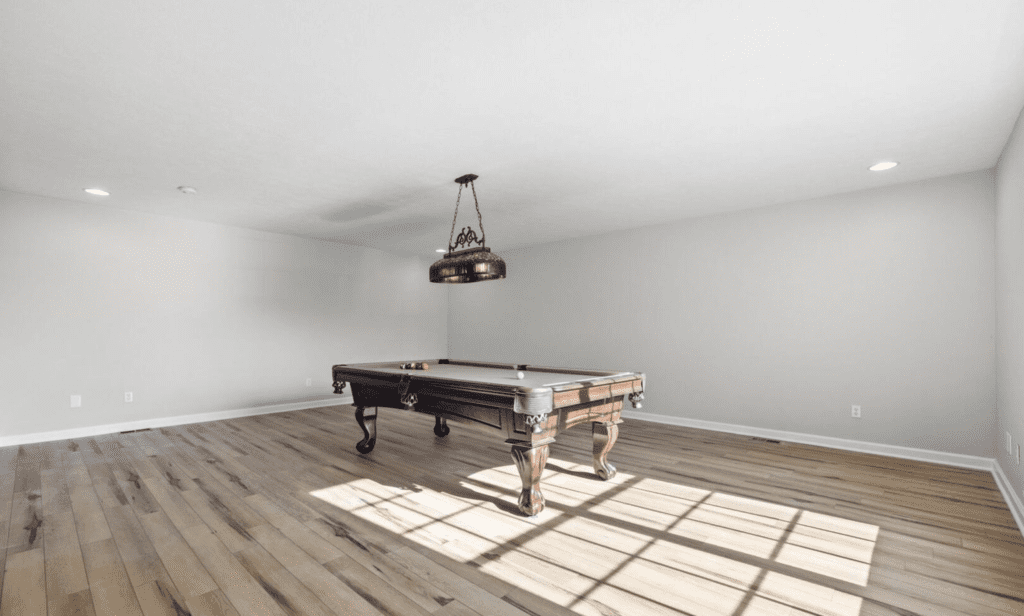 A rustic pool table in a bright, empty room with wooden floors.