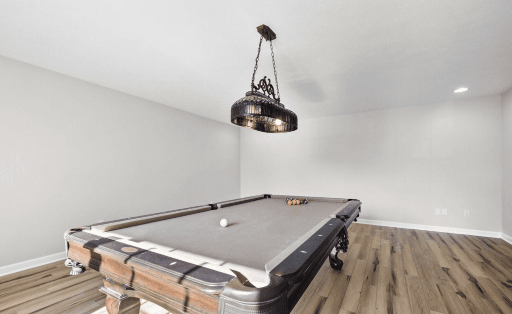 Elegant pool table with modern lighting in a minimalistic room.