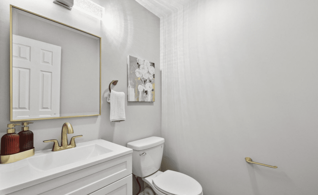 Minimalist bathroom with white walls, a toilet, and a vanity with a mirror.