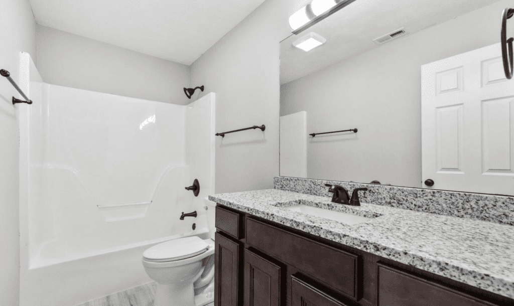 Bright bathroom with granite countertop and dark wood cabinets.