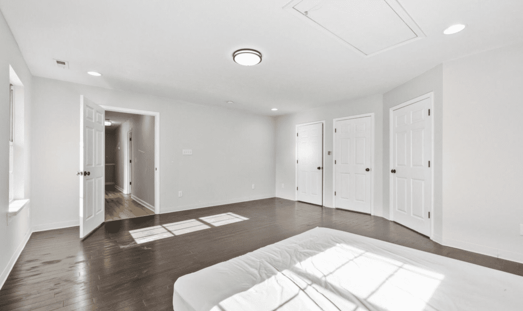 Bright, empty room with hardwood floors and white walls.