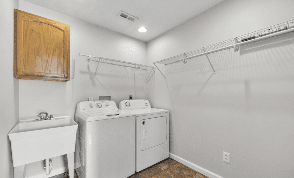 Bright laundry room with washer, dryer, and wall-mounted drying racks.