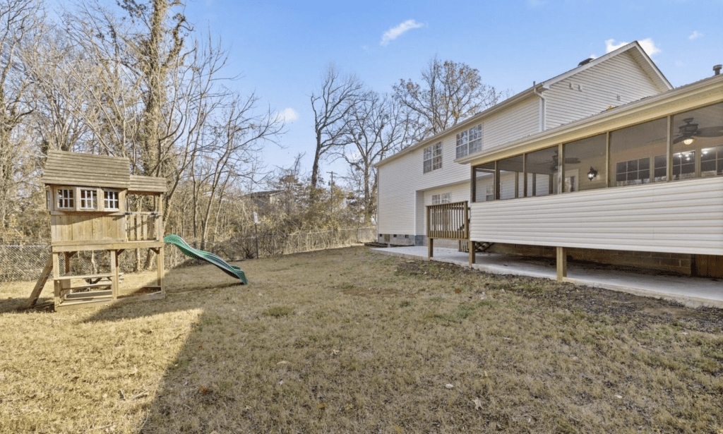 Backyard with a playset and porch on a sunny day.